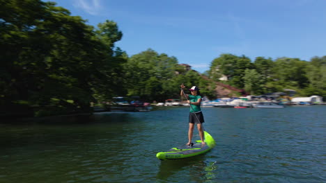 Una-Mujer-Monta-Una-Tabla-De-Remo-Sola-En-Un-Hermoso-Lago-Con-Una-Cámara-Dando-Vueltas