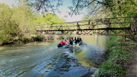 Holiday-Day-trippers-river-boat-speeds-under-wooden-eco-trail-footbridge