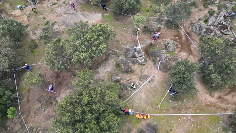 drone-flight-in-overhead-view-watching-a-stretch-of-cross-country-circuit-with-people-watching-the-event-behind-the-fencing-tapes-and-a-motorcyclist-performing-on-the-circuit-there-is-an-influx