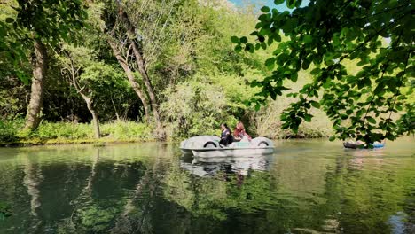 Boys-in-canoe-chase-girls-in-Pedalo,-fun-water-river-adventure-activity