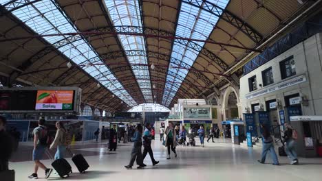 Commuters-and-travelers-with-luggage-walking-under-the-large-arched-roof-of-a-busy-railway-station