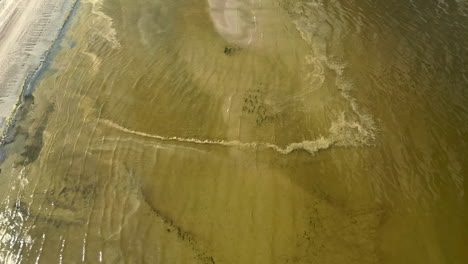 Sandstrand-Und-Flaches-Grünes-Wasser-Mit-Sanften-Wellen-In-Einer-Ruhigen-Küstenlandschaft,-Luftaufnahme