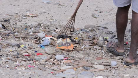 Mann-Sammelt-Plastikmüll-Mit-Rechen-Landwirtschaftswerkzeug-In-Carter-Road-Beach-Mumbai-Indien-Nahaufnahme