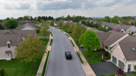 Aerial-tracking-shot-car-on-road-in-housing-area-during-cloudy-day