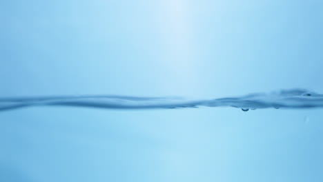 Waves-of-crystal-clear-blue-mineral-water,-creating-some-tiny-bubbles-and-droplets-of-in-a-water-tank