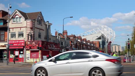 Calle-Cerca-Del-Estadio-Old-Trafford-Con-Coches-Y-Ciclistas-En-Manchester,-Reino-Unido