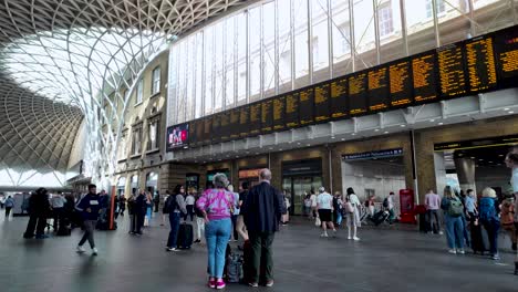 Commuters-and-travelers-with-luggage-Kings-cross-station,-showing-movement-and-the-structure's-modern-architecture