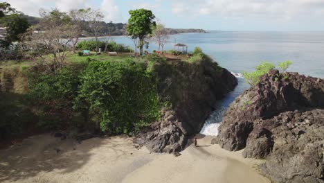 Una-Chica-Con-Un-Vestido-De-Playa-Negro-Camina-En-Un-Canal-De-Playa-Con-Un-Fuerte-Con-Vistas-Al-Océano