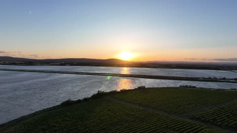 Sunset-behind-the-Mediterranean-Pyrenees-at-Manguelone-France-with-lagoon,-Aerial-dolly-left-shot