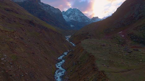 4K-Rückflug-Mit-Einer-Drohne-Entlang-Eines-Gletscherflusses-Mit-Atemberaubendem-Himmel-Und-Schneebedeckten-Himalaya-Bergen