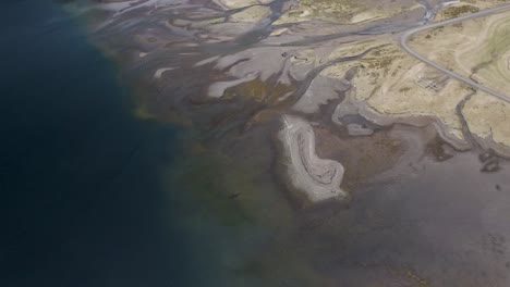 Aerial-tilt-up-shot-of-Mjoifjordur-Fjord-with-river-delta-on-Iceland-Island