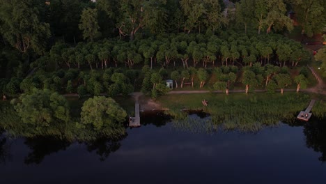 Una-Impresionante-Vista-Desde-Un-Dron-De-La-Aldea-De-Katvari-Al-Atardecer,-Destacando-El-Tilo-Katvari-Junto-Al-Lago