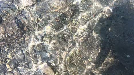 Underwater-sea-water-rocky-coast,-small-pebble-stone-under-clear-water
