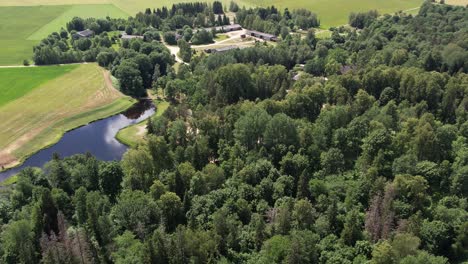 Vista-Aérea-Del-Escenario-De-Diklu-En-La-Aldea-De-Dikli,-Que-Muestra-El-Lugar-De-Actuación-Al-Aire-Libre-Rodeado-De-Exuberante-Vegetación-Y-Edificios-Cercanos.