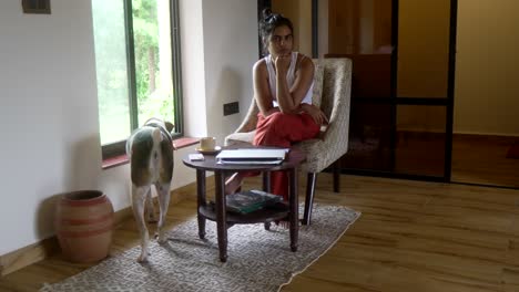 Woman-sits-pensively-in-a-cozy-living-room-with-a-dog-nearby