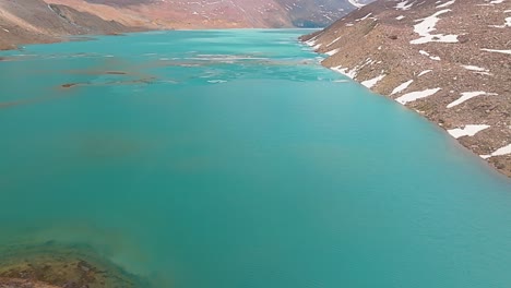 4K-pull-back-drone-shot-across-a-magical-Saphire-blue-Ghepan-lake-with-an-island-in-the-middle