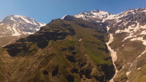 4K-Schwenk--Und-Rückfahr-Drohnenaufnahme-Eines-Gefrorenen-Bachs,-Der-Den-Mächtigen-Himalaya-Berg-Hinunterfließt