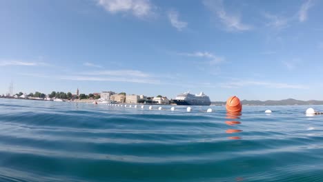 Schwimmen-In-Der-Warmen-Blauen-Adria-Mit-Stadtpanorama-Von-Zadar-Im-Hintergrund,-Kroatien-Am-Morgen