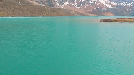 4K-Drohnenflug-über-Einen-Saphirblauen-Gletschersee-Mit-Einer-Insel-In-Der-Mitte,-Die-Den-Blick-Auf-Die-Schneebedeckten-Gipfel-Des-Himalaya-Freigibt