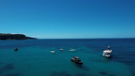 Touristische-Motorboote-Und-Segelboote-Schwimmen-In-Der-Blauen-Bucht-Des-Ionischen-Meeres-In-Der-Nähe-Des-Piers-In-Himaras-Felsiger-Küstenschönheit