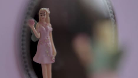 Close-up-of-a-miniature-fairy-doll-in-soft-focus-with-a-spinning-motion,-gentle-pastel-backdrop