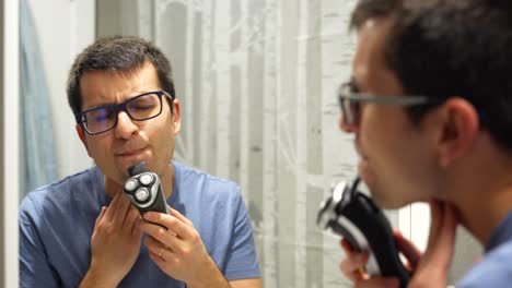 Close-up-shot-of-white-man-with-glasses-shaving-beard-with-an-electric-razor