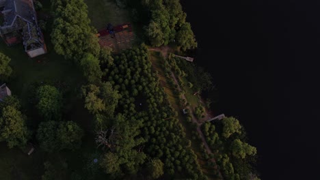 A-stunning-drone-view-of-Katvari-village-at-sunset,-highlighting-the-Katvari-linden-tree-by-the-lake