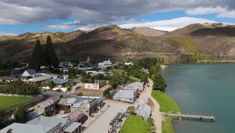 Drone-view-of-township-of-Cromwell-under-clouds-with-beautiful-landscape-of-mountains-at-background-in-New-Zealand