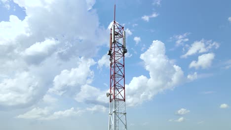 Torre-De-Telefonía-Celular-5g-Roja-Y-Blanca-Con-Cielo-Azul-Y-Nubes-Blancas-En-El-Fondo