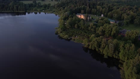 A-stunning-drone-view-of-Katvari-village-at-sunset,-highlighting-the-Katvari-linden-tree-by-the-lake