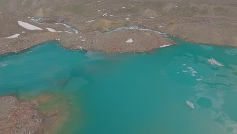 4K-Drohnenaufnahme-Eines-Teilweise-Zugefrorenen-Himalaya-Sees-Mit-Einem-Daraus-Entspringenden-Fluss