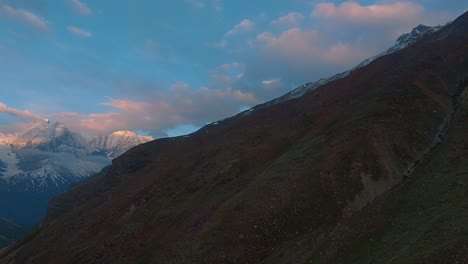 4K-drone-Panning-shot-revealing-sunrise-sky,-snow-capped-mountains-,-rivers-running-down-from-Glaciers