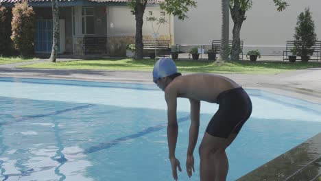 Young-Man-Swimmer-Wear-Goggles-And-Cap-Jumping-Into-Swimming-Pool-And-Dive