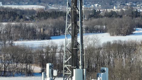 Closeup-drone-shot-of-transmission-tower-in-snowy-winter-landscape-of-american-town