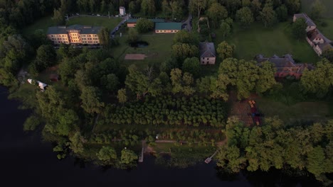 A-stunning-drone-view-of-Katvari-village-at-sunset,-highlighting-the-Katvari-linden-tree-by-the-lake