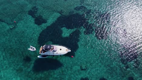 Eine-Yacht-Mit-Wassersportausrüstung-In-Der-Klaren-Blauen-Lagune,-Drohnenaufnahme