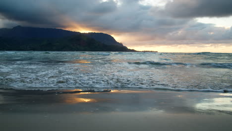 Close-Up-of-Waves-Rolling-Onto-Reflective-Hanalei-Sand-at-Moody-Sunset-in-Slow-Motion