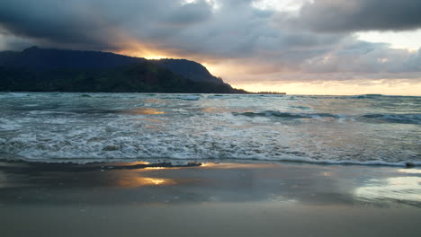 Nahaufnahme-Von-Wellen,-Die-Bei-Stimmungsvollem-Sonnenuntergang-In-Zeitlupe-Auf-Den-Reflektierenden-Hanalei-Sand-Rollen