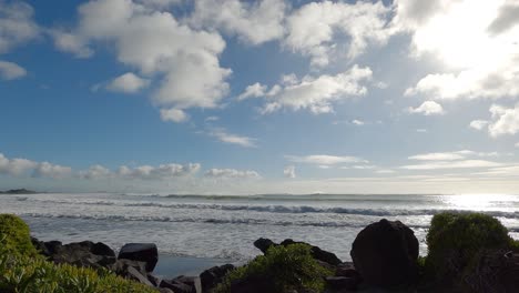 Sunlight-reflects-on-sea-as-white-water-waves-hit-rocks---Scarborough-Bay,-New-Zealand