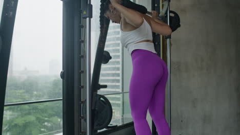 Mujer-Joven-Haciendo-Sentadillas-Pesadas-En-El-Gimnasio,-Manteniéndose-En-Forma,-Entrenamiento-De-Cuerpo-Completo