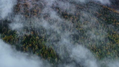 Fall-autumn-Saastal-Saas-Fee-Switzerland-aerial-drone-mountain-larch-forest-peak-moody-clouds-layer-gray-grey-rainy-fog-mist-Swiss-Alps-mountain-peaks-glacier-valley-pan-motion