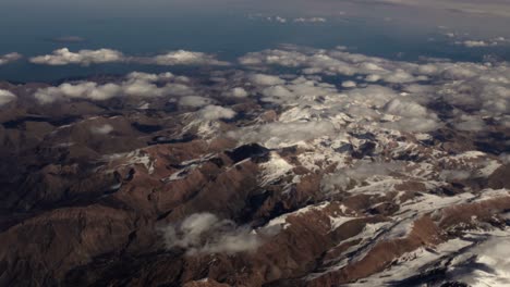Vista-Aérea-Desde-Un-Avión-Del-Paisaje-Montañoso-De-Irán-Cubierto-De-Nieve-En-Medio-Oriente