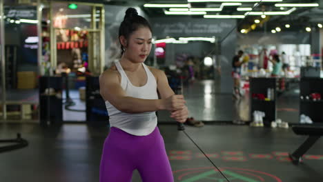 Asian-woman-doing-shoulder-pulls,-elastic-resistance-bands-training,-fit-female-working-out-in-gym