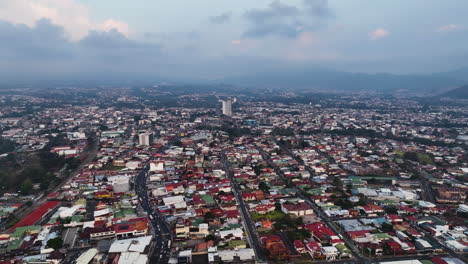 Aerial-overview-backwards-over-the-cityscape-of-San-Jose,-evening-in-Costa-Rica