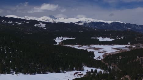 Mount-Blue-Sky-Evans-Marshdale-Evergreen-Colorado-aerial-drone-14er-Rocky-Mountain-North-Turkey-Creek-Rd-Red-Barn-homes-landscape-spring-snow-melting-morning-sunny-cloudy-forward-pan-up-reveal-motion