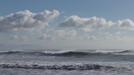 Surfer-Reitet-Eine-Welle-An-Einem-Sonnigen-Tag-Mit-Einer-Kulisse-Aus-Flauschigen-Cumulus-Wolken---Scarborough-Bay,-Neuseeland