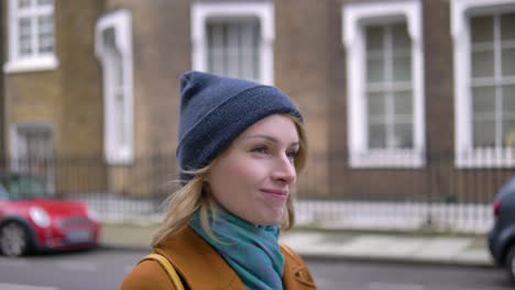 Side-closeup-view-of-a-happy-cheerful-positive-and-relaxed-young-Caucasian-woman-enjoying-the-weather,-walking-down-a-London-street-and-smiling-while-looking-around