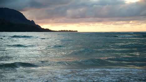 Las-Cambiantes-Olas-Del-Atardecer-Golpean-La-Madera-Flotante-En-La-Bahía-De-Hanalei-En-Cámara-Lenta-Con-Bali-Hai