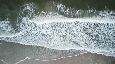 Strand-Drohnenaufnahme-Mit-Wellen,-Die-Von-Oben-Ans-Ufer-Krachen