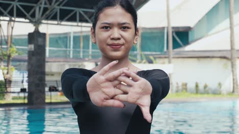 Close-up-shot-of-swimmer-stretching-her-arms-while-warming-up-by-outdoor-pool